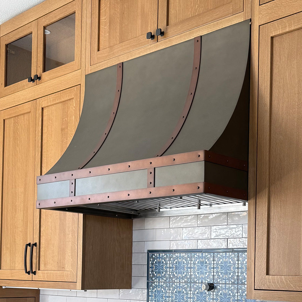 zinc and copper range hood with white oak cabinets