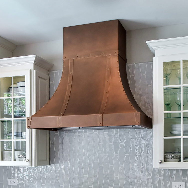 beautiful copper range hood in a white kitchen with tile backsplash