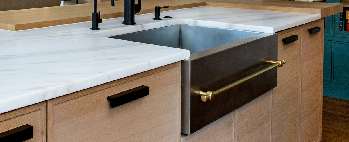 transitional kitchen with a metal farmhouse sink with brass towel bar