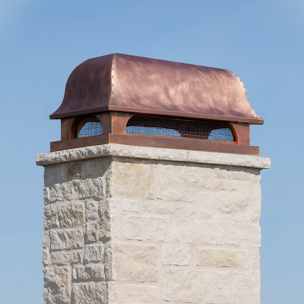 Copper decorative chimney cap on a stone chimney.