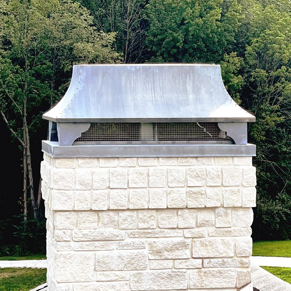 Decorative zinc chimney cap on white limestone chimney