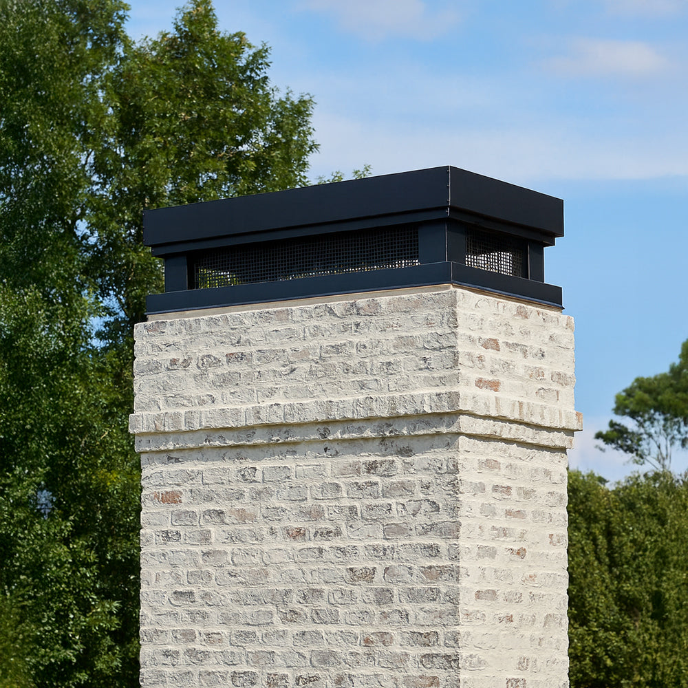 black modern chimney cap on a whitewashed brick chimney.
