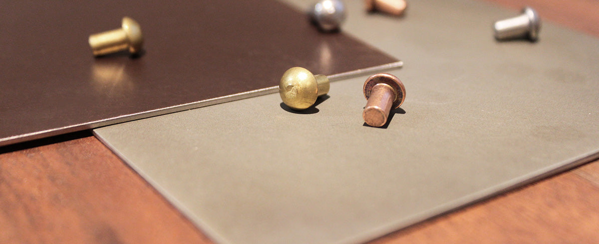 metal finish samples with rivets sitting on a wooden desk