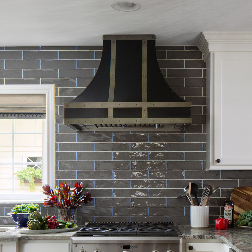 Black sweep metal range hood installed in high-end kitchen